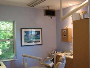 Empty dental chair in dental office facing open window.