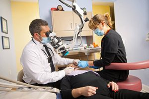 Dr. Klym and his assistant working on a patient in a dental chair.