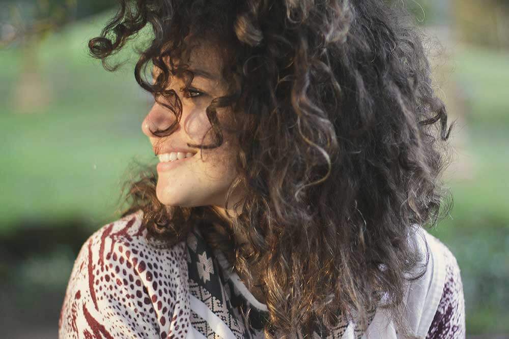 Young woman with dark curly hair smiling