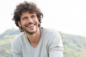 A younger man outside smiling and looking up