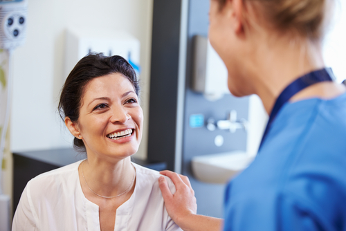 A doctor with her hand on her patients should while the patient is smiling