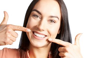 woman smiling and pointing at teeth