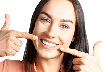 woman smiling and pointing at teeth