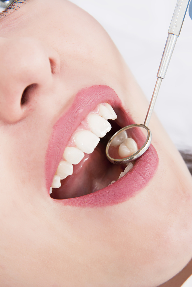 dentist examining patient's teeth with dental mirror