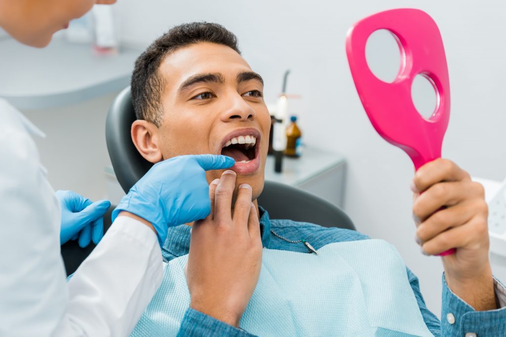 patient observing his smile in a hand mirror