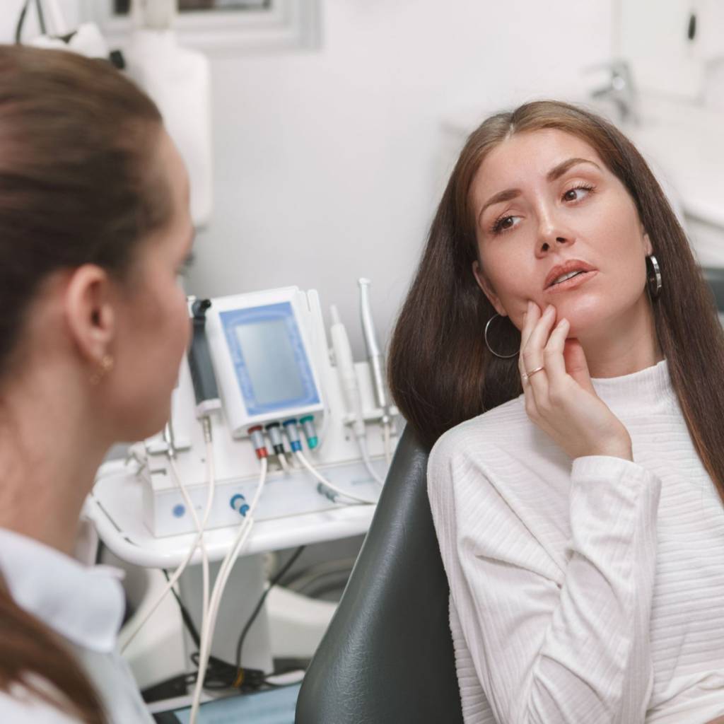 patient holding jaw in pain while speaking to dentist