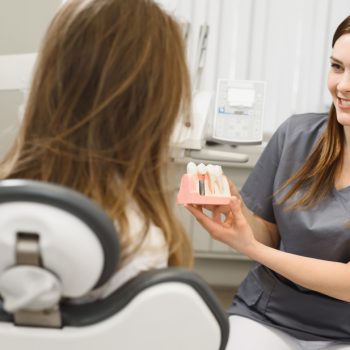 dentist showing patient a model of implants