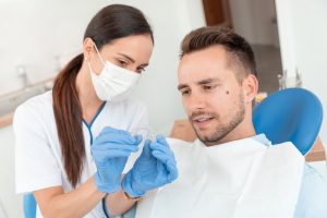 dental assisstant showing man a clear aligner