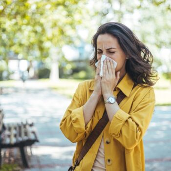 woman blowing nose in park