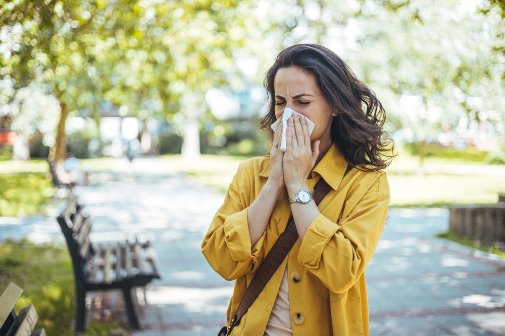 woman blowing nose in park